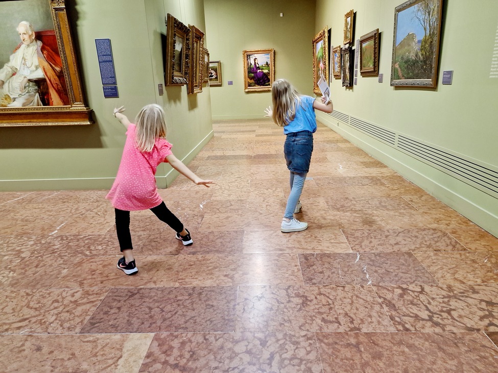gyerekek háttal, vicces pózokban a múzeumban