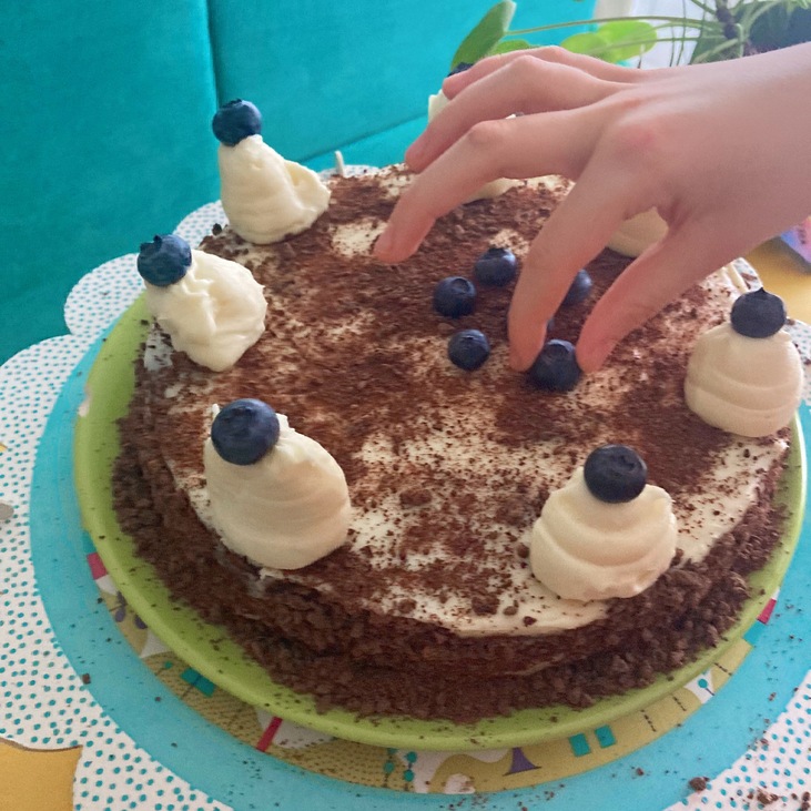 kisgyerek kéz pakolja az áfonyát a tortára