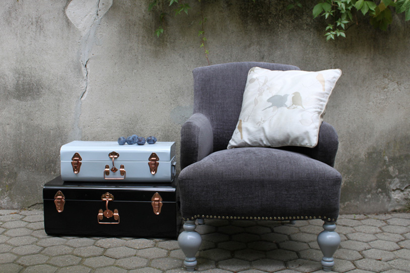 Szürke vintage fotel és színes fém bőröndök, rózsaarany csatokkal a Vintagechic online galériából