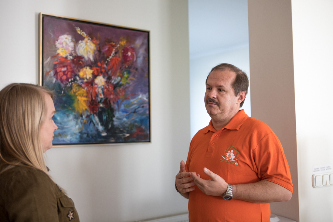 Dr. Benyó Gábor és Tóth Flóra egy virágokat ábrázoló festmény előtt állnak a Tábitha Házban