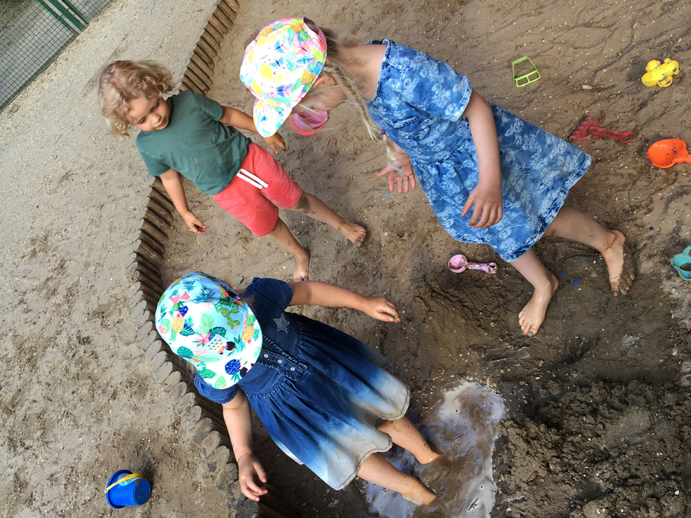 gyerekek állnak a sártengerré változott homokozóban
