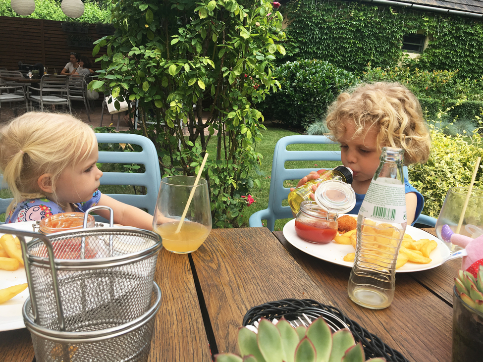 két kisgyerek ül az asztalnál félig üres tányérok mellett