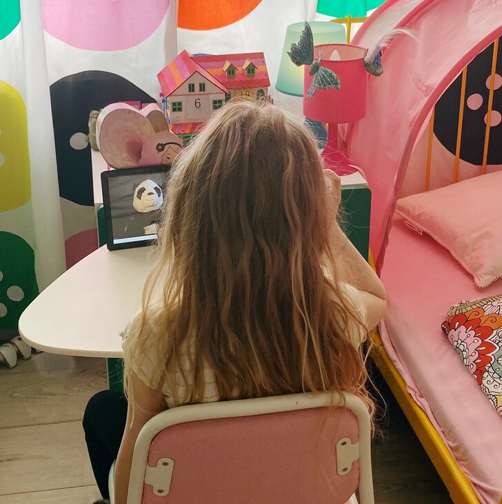 kislány ül egy tablet előtt, ahol online óra folyik