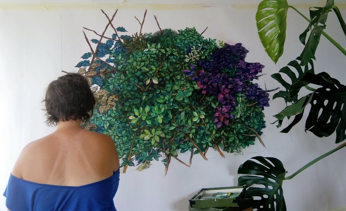 Tétnyi Gabriella háttal áll részletgazda, növényeket ábrázoló alkotása előtt