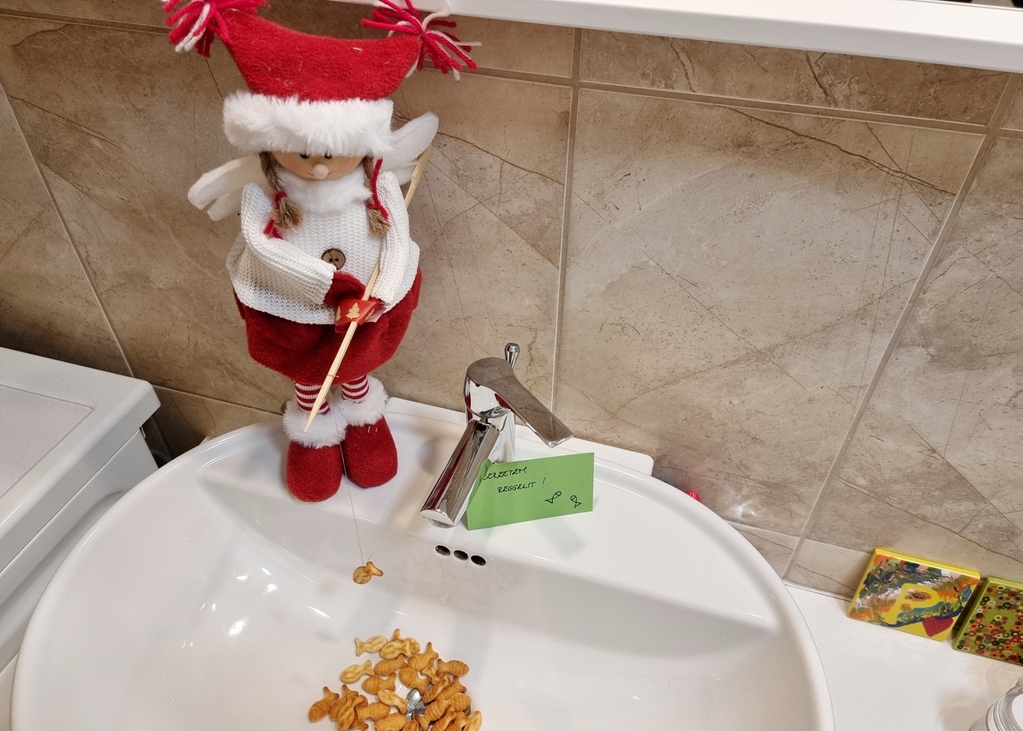 egy karácsonyi manó a mosdókagylóból pecázza ki a halacska krákereket